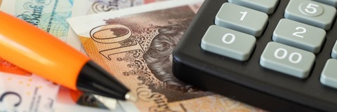 a calculator and pen lying on monetary notes