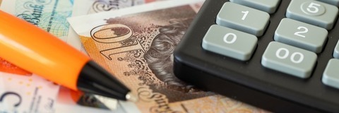 a calculator and pen lying on monetary notes