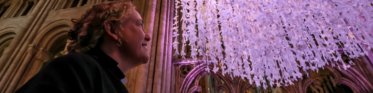 Person looking up at an art installation lit in purple