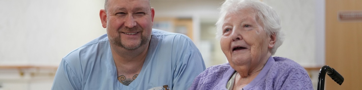 Image of an elderly lady sitting in her wheelchair, sitting next to a member of staff from adult social care.