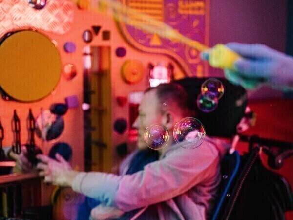 A man reaching out and touching objects in a sensory room.