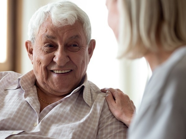 An image of a older man smiling at a woman sitting next to him.