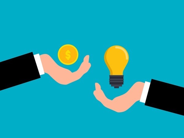 a blue background with one hand holding a coin and another hand holding a lightbulb